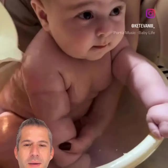 Küvette keyifle banyo yapan ve başı annesi tarafından nazikçe desteklenen mutlu bir bebek